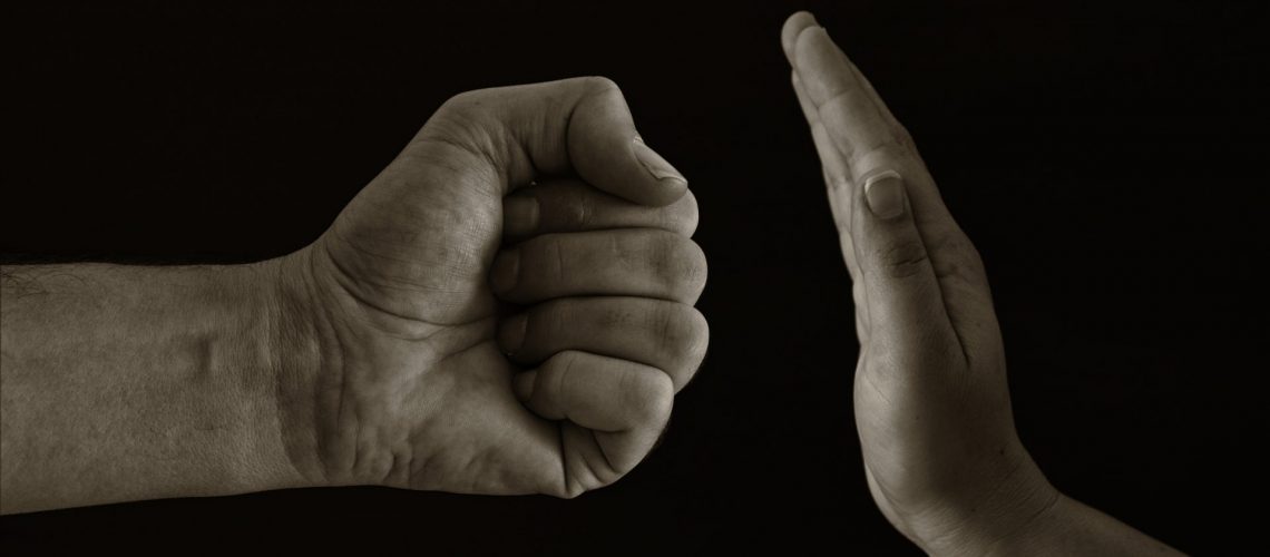 Image of male fist and female hand showing STOP. Domestic violence concept against women. Black and white photo